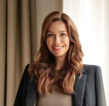 Smiling woman with light brown top and gray blazer.